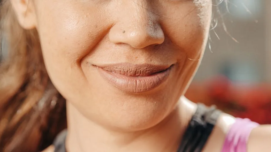 An extreme close-up of a smiling woman's lips and nose, capturing natural beauty and skin texture.